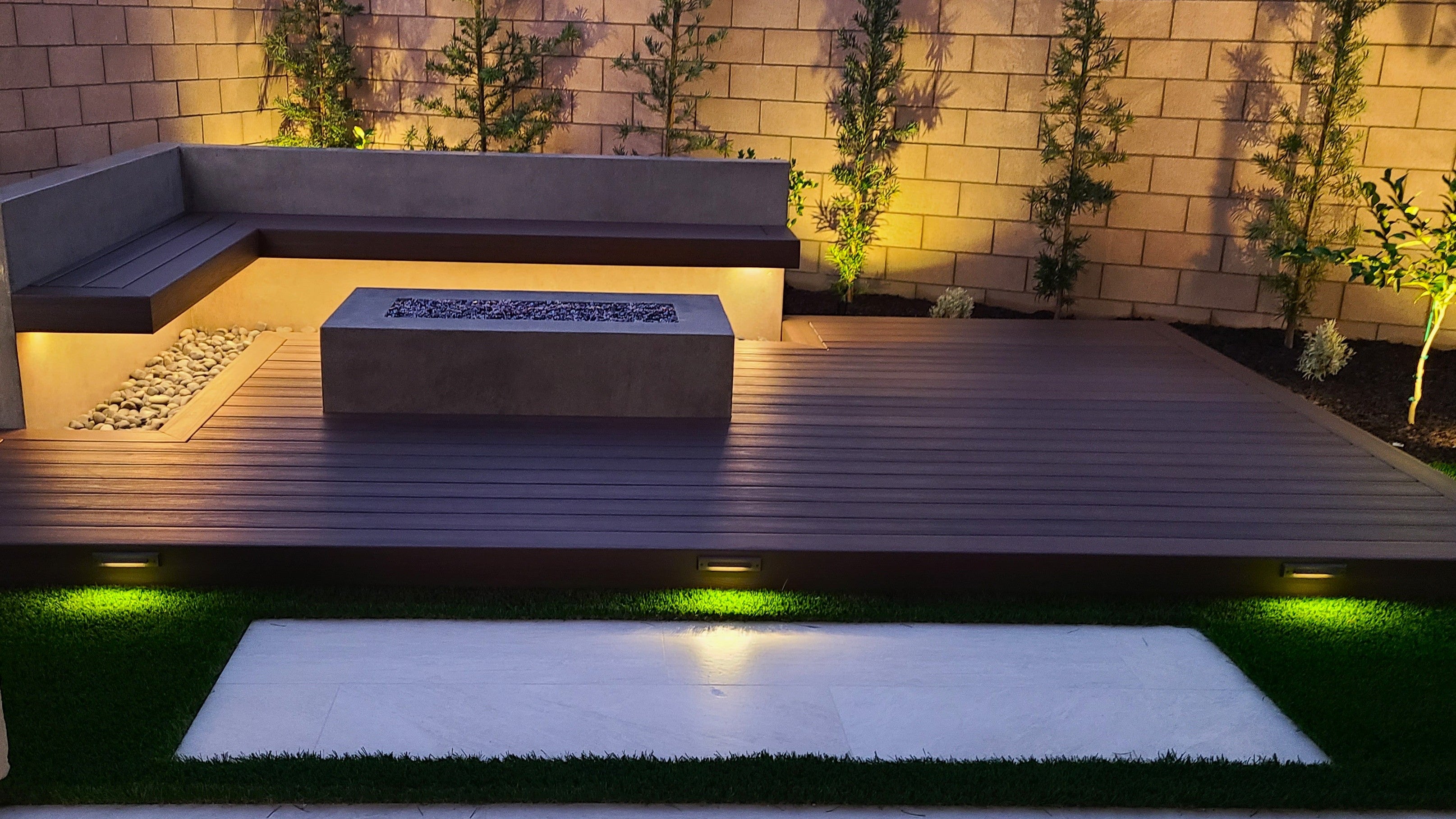 Modern outdoor patio with fire pit, seating area, and decorative plants.