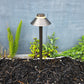 Garden lamp post with plants and mulch against a gray wall