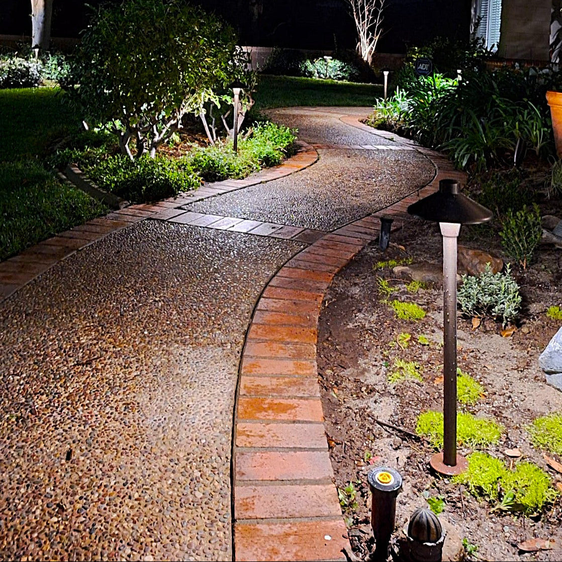 Winding garden path with decorative stones and lighting fixtures in a well-maintained garden.