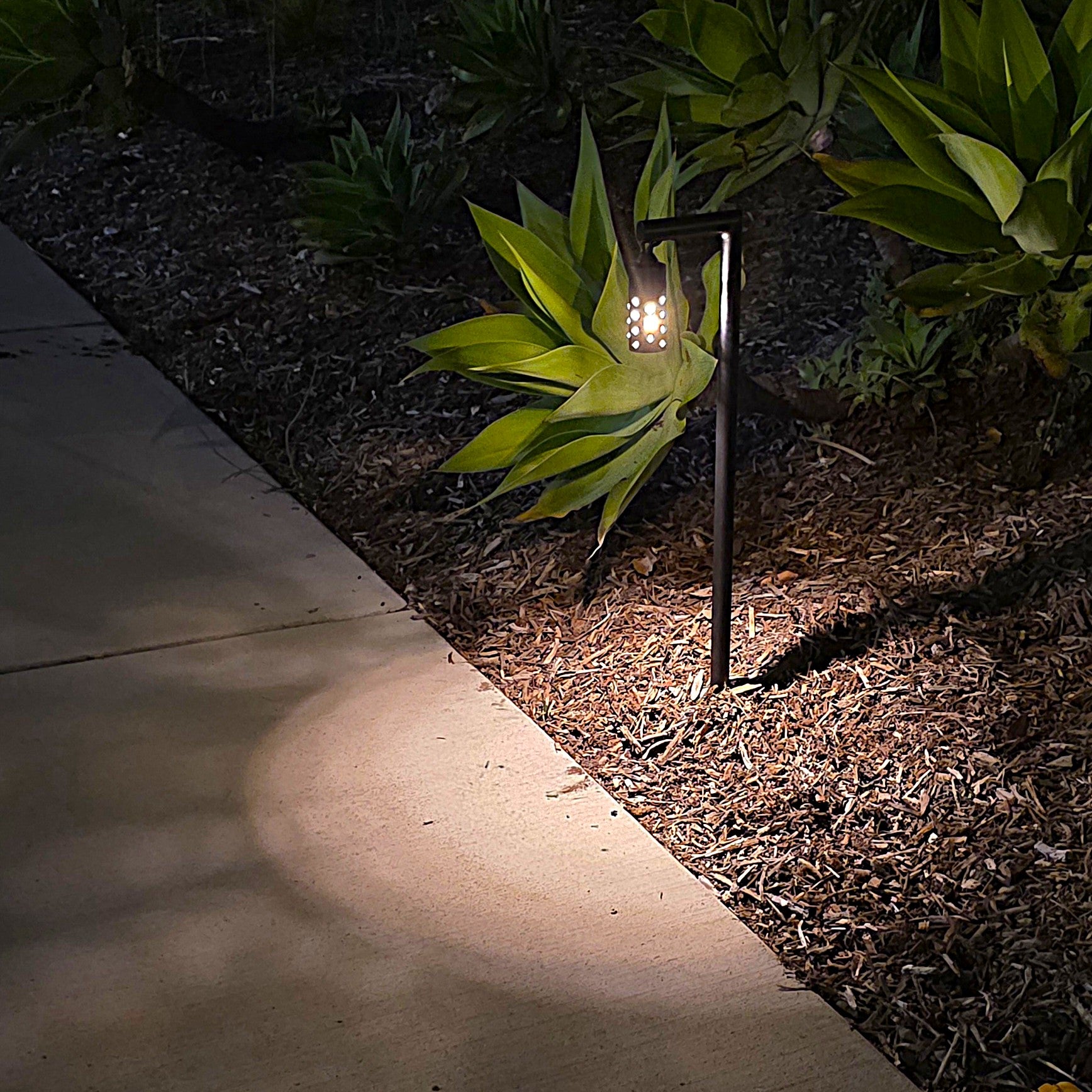 Pendule solid cast brass black lantern path light illuminating a landscaped walkway with warm LED glow.